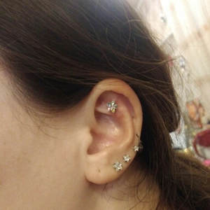 Close-up of ear piercings with 316L stainless steel flower and star stud earrings