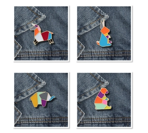 Détail de pins émaillés animaux origami colorés incluant lapin et éléphant sur du denim