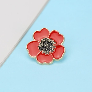 Detail of red enamel flower brooch with gold plating and delicate black center stamen