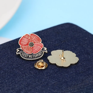 Detail of red poppy enamel brooch with Lest We Forget ribbon and golden butterfly clutch