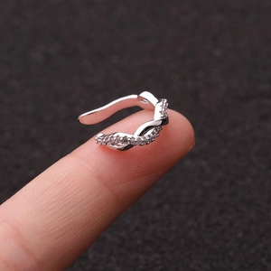 Detailed view of a silver U-shaped ear cuff with sparkling zircon on a finger