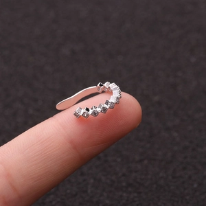 Macro shot of silver micro-paved ear cuff held on a fingertip with detailed crystal inlay