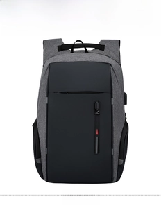 Vista frontale di uno zaino business grigio con porta USB esterna e dettagli zip rossi