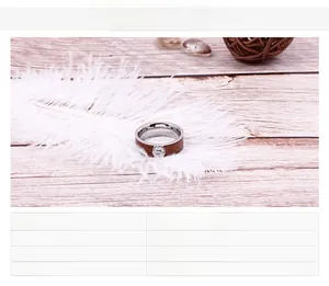 Detail of stainless steel ring with wood grain inlay and small center ornament