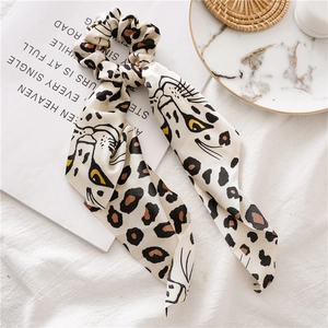 Detail of leopard print silk scarf scrunchie on a stylish marble lifestyle background