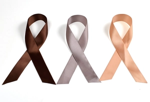 Close-up of three satin ribbons in dark coffee, grey, and champagne with smooth texture