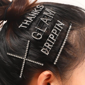 Close-up of sparkling rhinestone hairpins with THANKS and GLAM lettering in dark hair