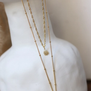 Close-up of double-layer gold star pendant necklace on a white ceramic display stand