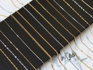 Detail shot of assorted gold and silver steel necklaces on a black display stand