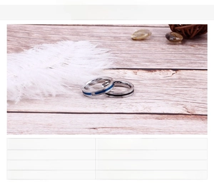 Detailed view of thin stainless steel rings with blue and black stripes and zircon inlay