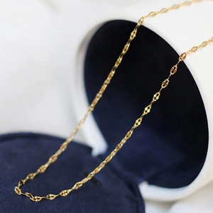 Macro shot of gold-plated lip chain link necklace on dark velvet jewelry box