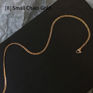 Detail of a thin gold cuban chain necklace with lobster clasp on a dark background