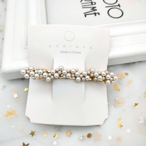 Détail d'une élégante pince à cheveux dorée avec perles sur fond de tulle étoilé