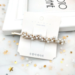 Gros plan sur une barrette dorée ornée de perles blanches sur un fond en tulle élégant