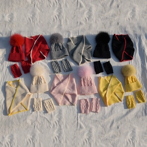Flat lay of colorful knit hat, scarf and glove sets with fluffy pom-poms for children
