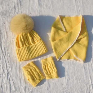 Macro shot of bright yellow knitted winter set with faux fur pompom for kids
