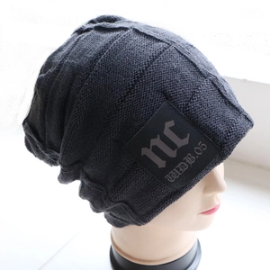 Close-up of dark grey knitted beanie featuring nc leather patch and thick ribbed texture