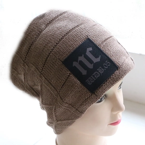 Macro detail of dark brown knit beanie with texture and NC leather patch decoration