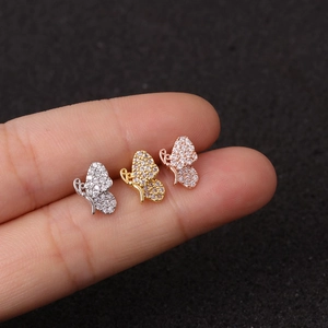 Detailed close-up of three dainty butterfly stud earrings in silver, gold, and rose gold