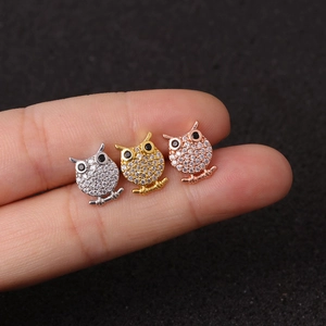 Sparkling owl-shaped cartilage studs in silver, gold, and rose gold finishes on fingers
