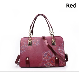 Detail of red paisley handbag showing leather handles with gold metal chain accents