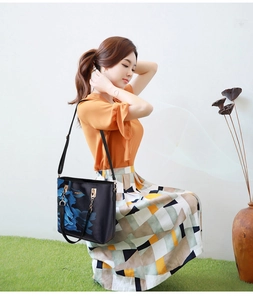 Detail view of black handbag featuring blue floral print and elegant gold hardware chain