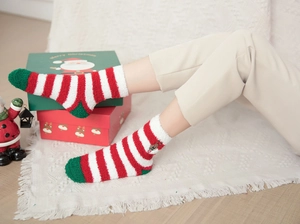 Close-up of thick coral fleece Christmas stockings with festive stripes on white rug