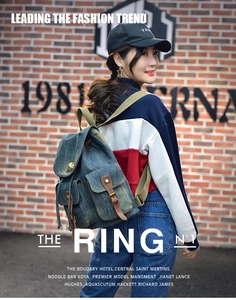Zaino in denim blu con fibbie in pelle marrone e tasche multiple su sfondo di mattoni rossi