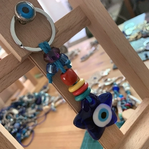 Detailed view of evil eye star charm keychain with colorful beads on wooden stand