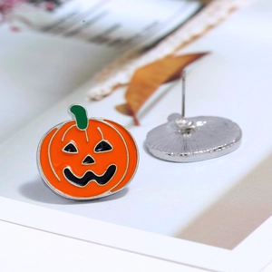 Detailed close-up of orange pumpkin stud earrings with green stems and black enamel faces