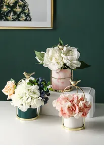 Close-up of birdcage-style flower pots with gold metal frames and ceramic vases