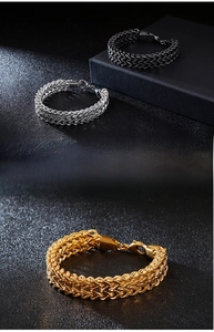 Detail of woven stainless steel chain bracelets in silver, gold, and black with lobster clasp