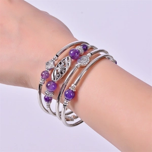 Detailed shot of layered silver bracelet with purple amethyst beads on a model's wrist