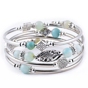 Detail of bohemian layered bracelets with turquoise, tiger eye stones and silver floral charms