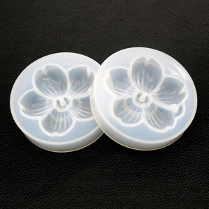 Dettaglio di due stampi in silicone a forma di fiore di ciliegio su pelle nera strutturata