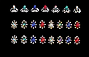 Detailed view of alloy crown and flower nail charms with colorful crystals on black background