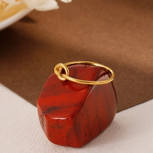 Minimalist gold knot stainless steel ring displayed on a red natural gemstone base