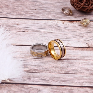 Polished stainless steel striped rings in gold and silver finish on wooden texture