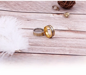 Two-tone stainless steel rings on rustic wood background with feathers and stones