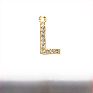 Macro view of gold brass letter L pendant with micro-paved cubic zirconia stones