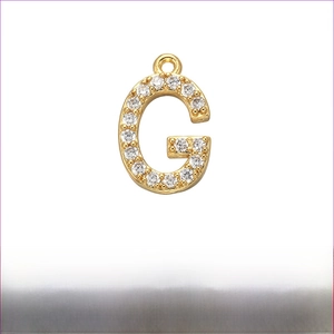 Detail of gold plated brass letter G pendant with micro paved white cubic zirconia stones