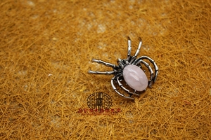 Detail shot of a spider brooch with a pink oval gemstone and silver-tone metal legs