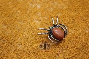 Detailed view of a spider-shaped silver brooch featuring a sparkling brown goldstone