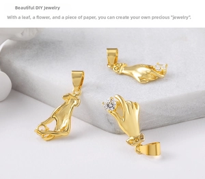 Detail of three gold hand-shaped pendants with white cubic zirconia on marble surface
