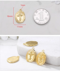 Macro view of gold oval cross pendant with size reference and textured metal detail