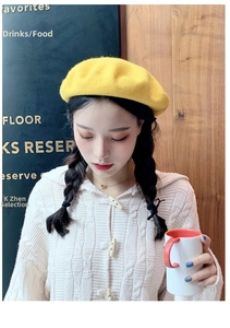 Detail of warm yellow wool beret paired with a cozy cable-knit sweater for winter style