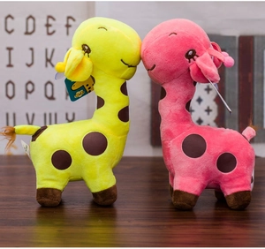 Detail of pink and yellow plush giraffes with spots leaning together on a wood surface