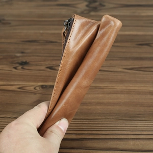 Macro shot of light brown crazy horse leather wallet with dark zipper on wood background