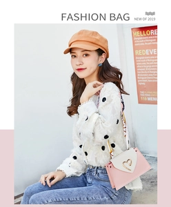 Detail of pink and beige crossbody bag featuring a golden heart-shaped metal lock closure