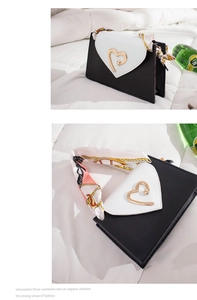 Close-up of contrast crossbody bag with heart-shaped flap and silk scarf handle detail